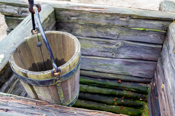 Old wooden well and a wooden bucket. The concept of rural areas and recreation in the village.