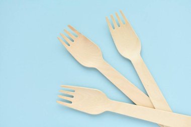 Mavi arka planda tek kullanımlık ahşap çatallar, doğal çevre dostu, sıfır atık ürün