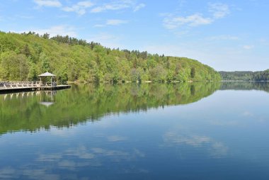 Güneşli bir günde mavi gökyüzünün altında sakin bir orman gölü..