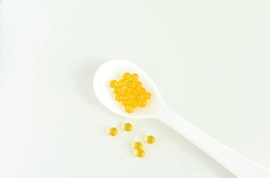 Beyaz kaşıkta D vitamini kapsülleri, gıda takviyeleri.