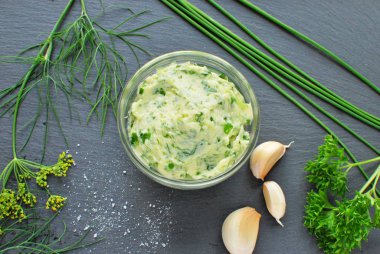 Baharatlı sarımsaklı tereyağı (dereotu, maydanoz, yeşil soğan). Siyah arkaplanda üst görünüm.