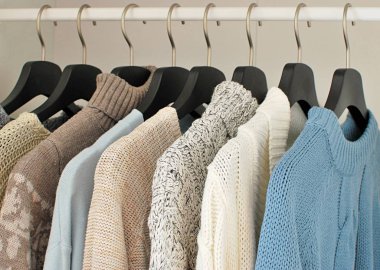 Gardıroptaki siyah askılarda asılı sıcak ve rahat kazaklar. Sonbahar kış modası.