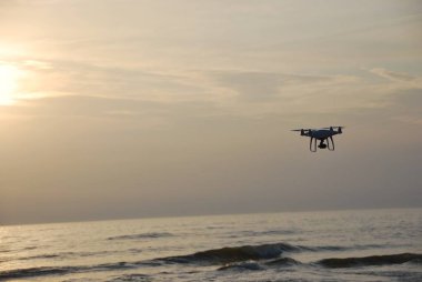 Drone akşam gökyüzünde denizin üzerinde uçuyor.