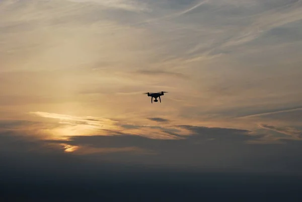 Drone is flying at sunset. Silhouette of drone in the sky.