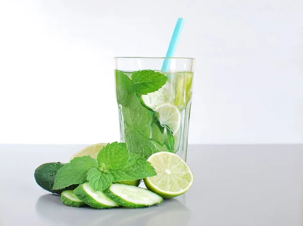 Infused water in big glass, with cucumber, mint leaves, green lemon, copy space.