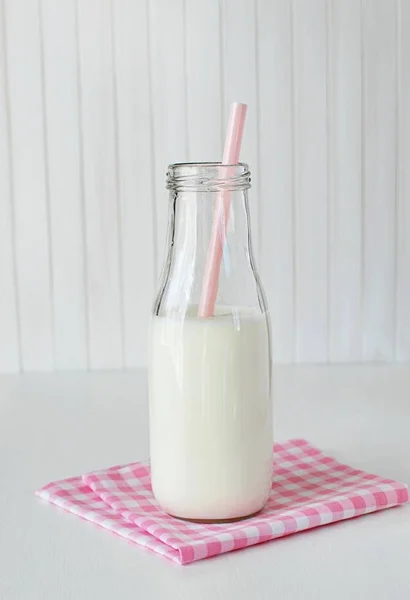 ピンクのチェックナプキンにわらで少し素朴なミルクボトル 子供用ミルク 白木の背景 — ストック写真