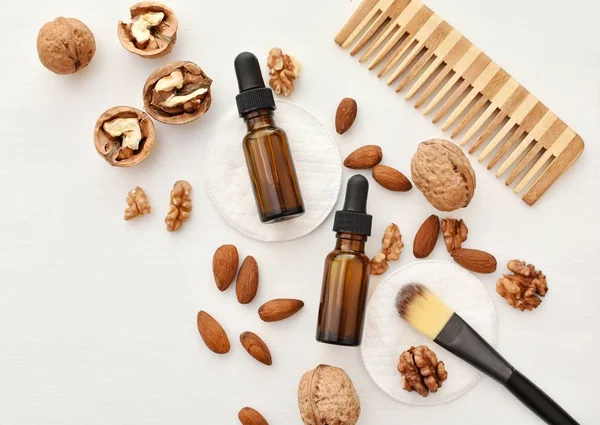 Natural organic walnuts and almond cosmetic oils and creams for skin and hair care, flat lay.