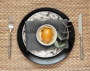 Asgari, kırsal, doğal Paskalya sofrası. Siyah tabak, keten peçete, renkli yumurta, okaliptüs dalı..