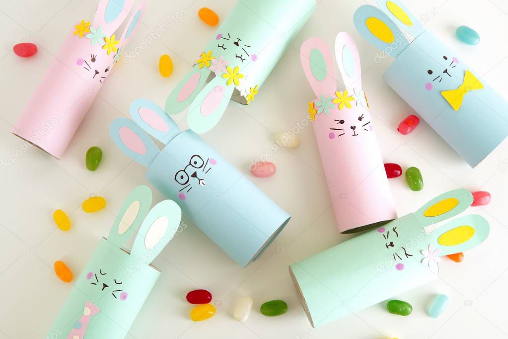 Flat lay with diy paper Easter bunnies and colorful candies, easy crafts for kids.          
