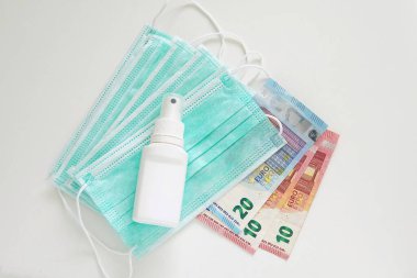 Pahalı tıbbi maske ve dezenfeksiyon sıvısı, avro para banknotları, koronavirüs koruma kavramı.
