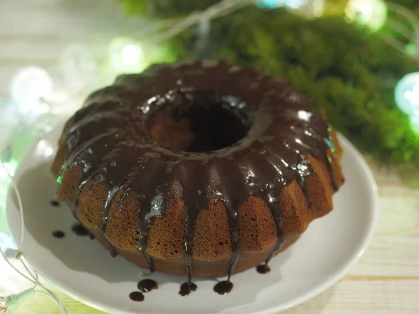 Cupcake rond au chocolat, glacé, sur un fond en bois avec des branches de sapin. Nous rencontrons Noël . — Photo