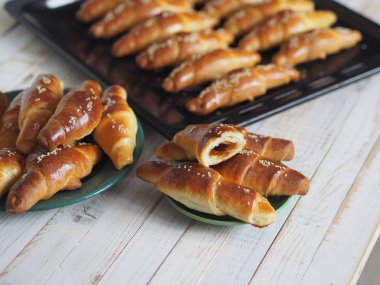 Fırından çıkan siyah bir ekmek tepsisinin üzerinde ev yapımı kızarmış simit. Yemek hazır. Susam tohumları serpiştirilmiş. Ev mutfağı.