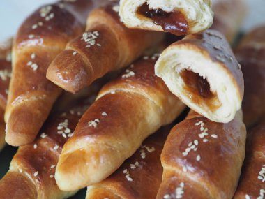 Fırından çıkan siyah bir ekmek tepsisinin üzerinde ev yapımı kızarmış simit. Yemek hazır. Susam tohumları serpiştirilmiş. Ev mutfağı.