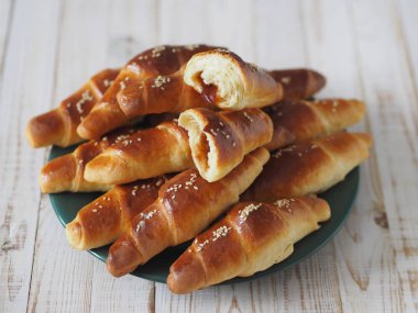 Fırından çıkan siyah bir ekmek tepsisinin üzerinde ev yapımı kızarmış simit. Yemek hazır. Susam tohumları serpiştirilmiş. Ev mutfağı.