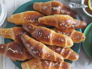 Fırından çıkan siyah bir ekmek tepsisinin üzerinde ev yapımı kızarmış simit. Yemek hazır. Susam tohumları serpiştirilmiş. Ev mutfağı.