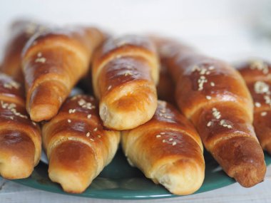 Fırından çıkan siyah bir ekmek tepsisinin üzerinde ev yapımı kızarmış simit. Yemek hazır. Susam tohumları serpiştirilmiş. Ev mutfağı.
