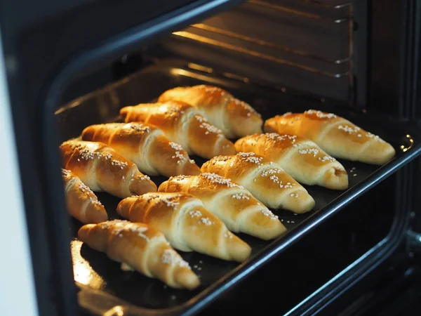 Ready-made toasted homemade bagels on a black baking sheet from the oven. Ready to eat. Sprinkled with sesame seeds. Home kitchen. — Stock Photo, Image