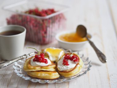 Ekşi kremalı börek ve kırmızı frenk üzümü. Tahta beyaz bir kırsal masada ballı soğuk algınlığı için terapi çayı. Ev mutfağı.