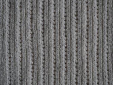 Örgü kumaş dokusu. Gri. Ön ve arka halkalarla basit örgü. Örgü iğnelerinin üzerine örgü örüyorum. Yatay çizgiler.