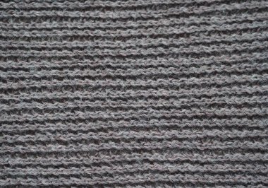 Örgü kumaş dokusu. Gri. Ön ve arka halkalarla basit örgü. Örgü iğnelerinin üzerine örgü örüyorum. Yatay çizgiler.