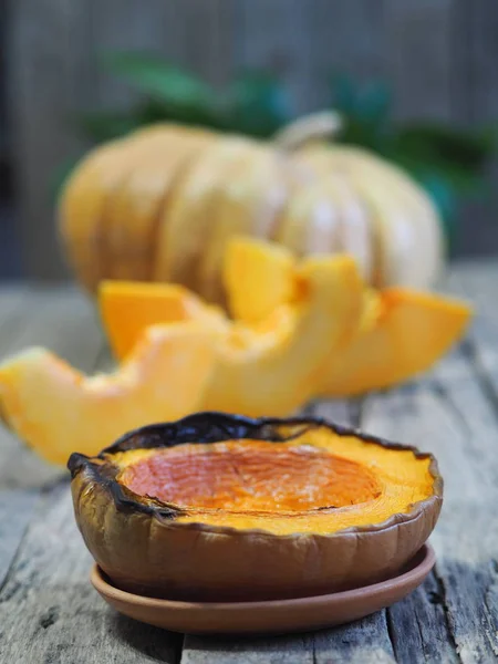 Cooking pumpkins. Home cooking, natural food for vegetarians. Traditional autumn pumpkin dishes. Grilled grilled pumpkin with spices on a background of raw whole pumpkin on a wooden background. — Stock Photo, Image