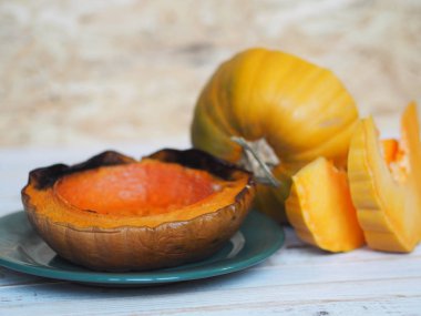 Balkabağı pişiriyorum. Ev yemekleri, vejetaryenler için doğal yiyecekler. Geleneksel sonbahar balkabağı yemekleri. Baharatlı ızgara balkabağı ve beyaz ahşap bir masada çiğ balkabağı..