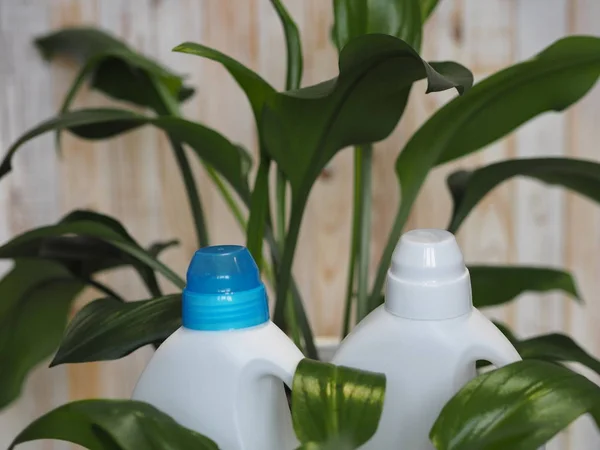 Zielone liście rośliny na tle plastikowych butelek detergentu. Koncepcja produktu bioorganicznego detergentu. — Zdjęcie stockowe