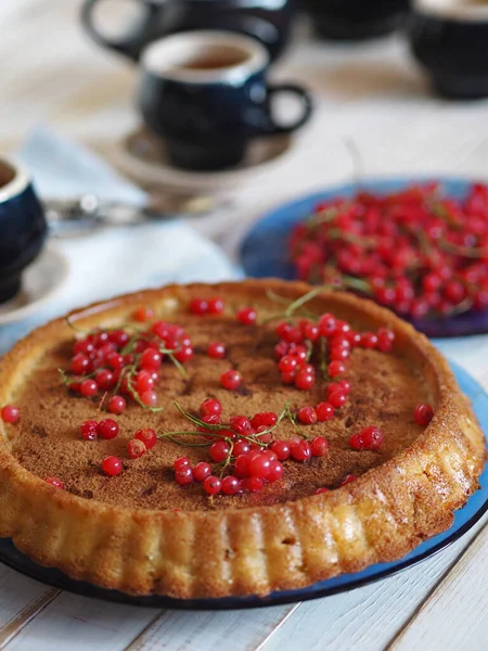 Open homemade pie with apples and red currants. Rustic cuisine. Blue coffee service on a wooden countertop. Rustic cuisine.