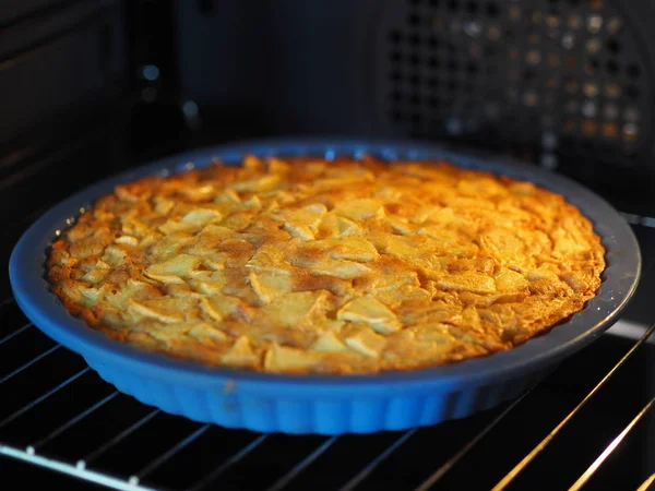 Une tarte maison ouverte aux pommes et aux groseilles rouges est cuite dans un four noir. Cuisine maison . — Photo