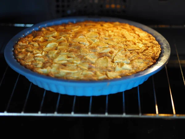 Une tarte maison ouverte aux pommes et aux groseilles rouges est cuite dans un four noir. Cuisine maison . — Photo