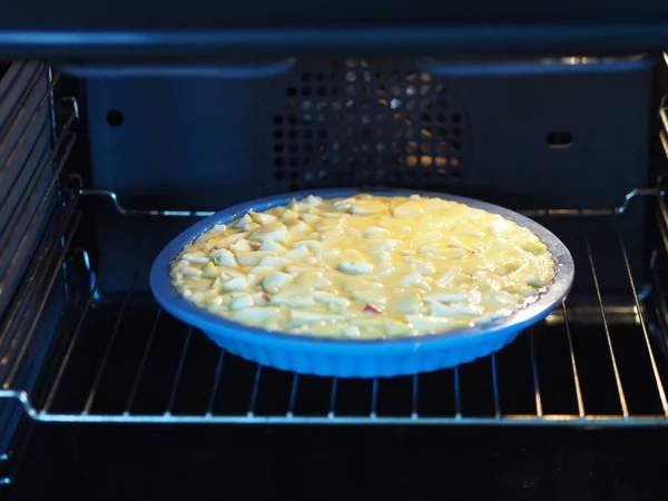 Un pastel casero abierto con manzanas y grosellas rojas se cocina en un horno negro. Cocina casera . —  Fotos de Stock