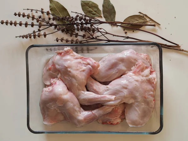 Carcass of raw rabbit meat on a glass baking sheet. Home cooking, cook at home.