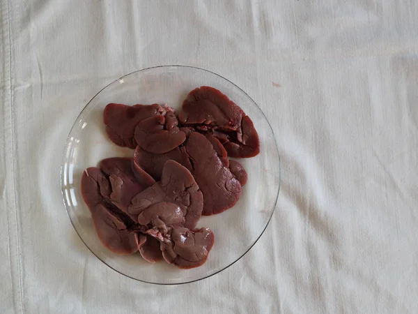 Rabbit liver on a glass baking sheet. We cut the rabbit into pieces. Home cooking, cook at home.
