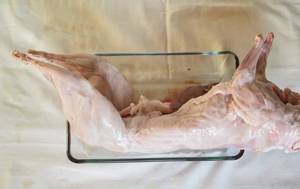 Carcass of raw rabbit meat on a glass baking sheet. Home cooking, cook at home.