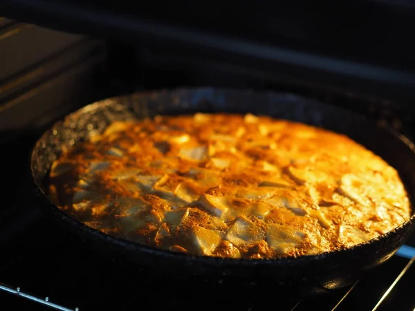 Домашня випічка. Круглий яблучний пиріг у чорній сковороді в духовці . — стокове фото
