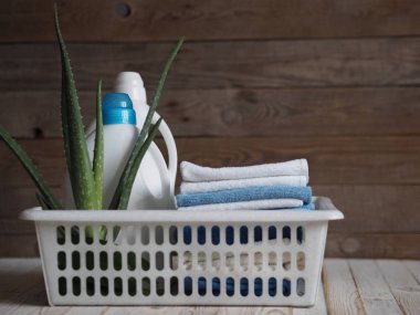 Çevre dostu doğal deterjan kavramı. Deterjan ve temizlik ürünleri, keten için plastik bir sepetin içinde ahşap bir arka planda aloe vera bitkisi ile. Köy.