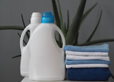 Çevre dostu doğal deterjan kavramı. Deterjan ve temizleyiciler, gri bir arka planda, plastik çamaşır sepetinde aloe vera bitkisi. Köy.