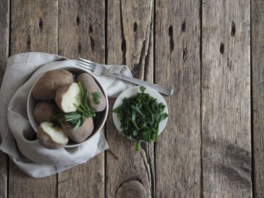 Dondurucudaki yeşilliklerle birlikte kabukta haşlanmış patates. Eski ahşap arka plan. Geleneksel yemek..