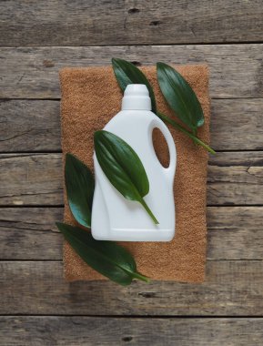 Yeşil yaprak şeklinde organik deterjan kavramı ve tahta doğal arka planda beyaz plastik bir deterjan şişesi. Ekolojik proje. Bitkilerin yeşil yaprakları. Çevre Tesisi.
