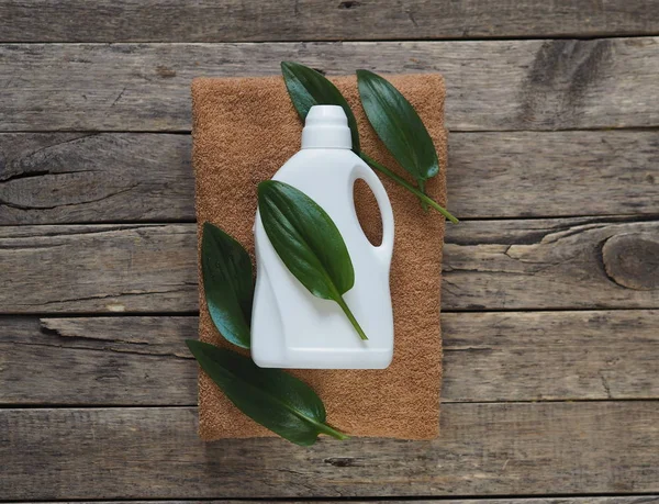 Koncepcja ekologicznego detergentu w postaci zielonego liścia i białej plastikowej butelki detergentu na drewnianym naturalnym tle. Projekt ekologiczny. Zielone liście roślin. Obiekty środowiskowe. — Zdjęcie stockowe