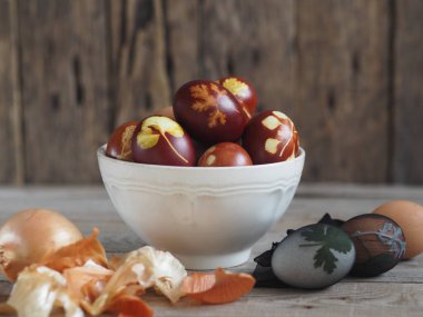 Paskalya yumurtaları eski ahşap bir arka planda taze otlarla birlikte soğan kabuğu boyadı. Yumurtaları eski çevre dostu yöntemle soyulmuş soğanla boyuyoruz..