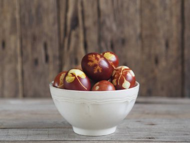 Paskalya yumurtaları eski ahşap bir arka planda taze otlarla birlikte soğan kabuğu boyadı. Yumurtaları eski çevre dostu yöntemle soyulmuş soğanla boyuyoruz..