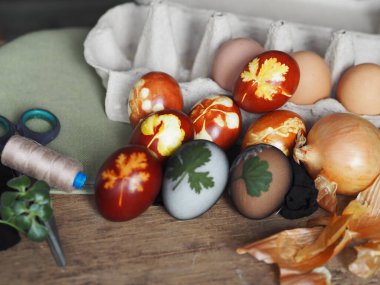 Paskalya yumurtaları eski ahşap bir arka planda taze otlarla birlikte soğan kabuğu boyadı. Yumurtaları eski çevre dostu yöntemle soyulmuş soğanla boyuyoruz..