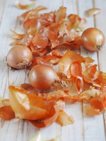 The use of onion skins in medicine and for coloring Easter eggs. Onion skin and onion on a wooden background. Onion is a storehouse of vitamin.