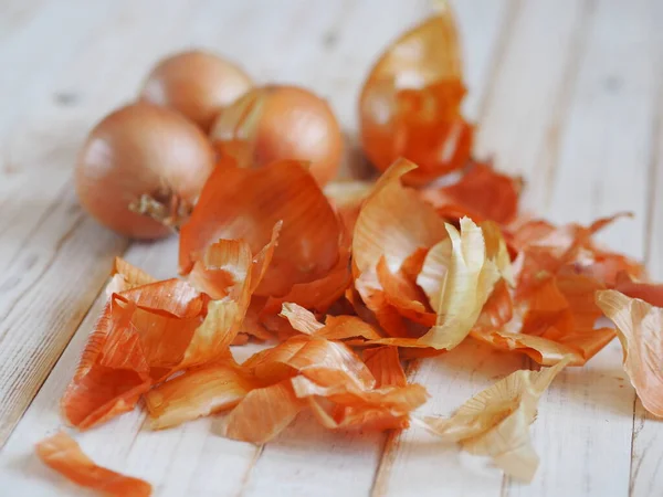 The use of onion skins in medicine and for coloring Easter eggs. Onion skin and onion on a wooden background. Onion is a storehouse of vitamin.