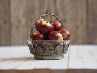 Paskalya. Paskalya soğanı kabuğu için yumurta boyamak. Geleneksel doğal renklendirme yöntemi. Ahşap arka planda yumurtalar. Metal vazo.