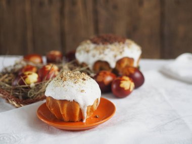 Paskalya. Geleneksel Paskalya hamur işleri, soğan kabuğuna boyanmış yumurtalar ve doğal bir masa örtüsünün üzerinde kurumuş çimen olan tavuk yuvalarının taklidi. Doğal malzemelerle serpiştirilmiş. Ahşap antik arkaplan. 