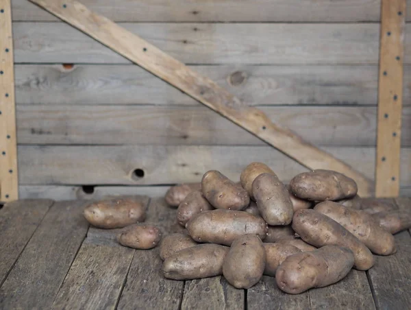 Kartoffelknollen auf einem hölzernen Hintergrund in Großaufnahme. Lagerung von Kartoffeln in einer Holzkiste. — Stockfoto