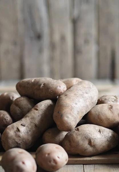 Kartoffelknollen auf einem hölzernen Hintergrund in Großaufnahme. Lagerung von Kartoffeln in einer Holzkiste. — Stockfoto