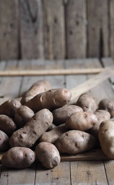 Kartoffelknollen auf einem hölzernen Hintergrund in Großaufnahme. Lagerung von Kartoffeln in einer Holzkiste. — Stockfoto